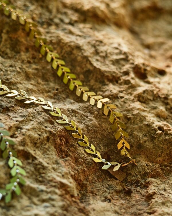 Close-up of a gold leaf design necklace placed on a rocky surface